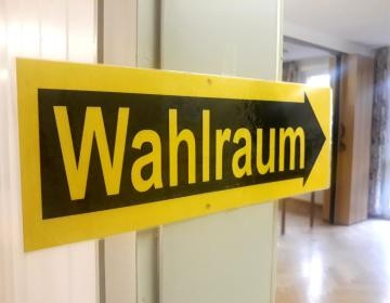 Ein Schild mit der schwarz-gelben Aufschrift "Wahlraum" weist den Weg ins Wahllokal 